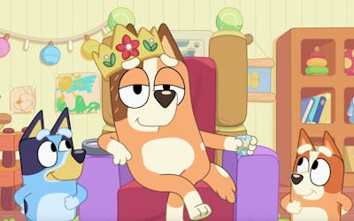 Chilli sits on a throne wearing crown, attended by Bluey and Bingo.