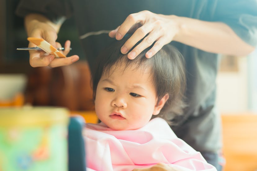 Baby girl gets first haircut from stylist, in a story about baby's first haircut captions.
