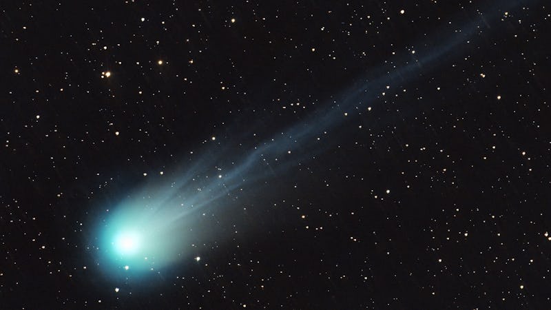 A comet shoots through the sky, it's bright bulb aglow and surrounded by a haze that falls back towa...