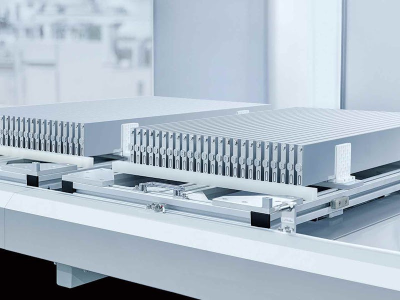 Two sleek, modern server units with ribbed exteriors sitting on a white rack in a clean, high-tech e...