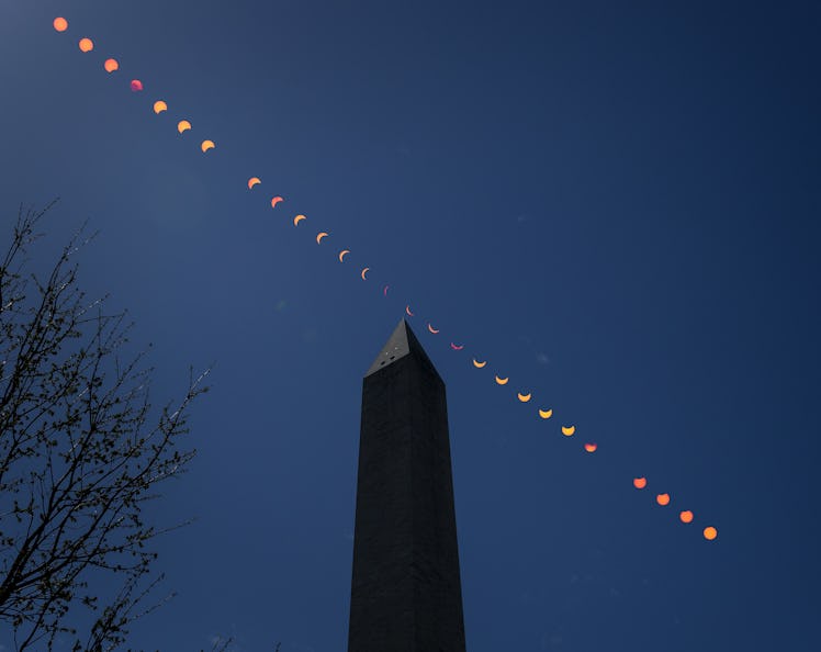 time-lapse photo of a total solare eclipse passing over a silhouette of the Washington Monument in n...