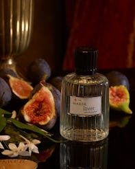 Elegant perfume bottle labeled "lover" by The Maker, surrounded by fresh figs and white flowers on a...