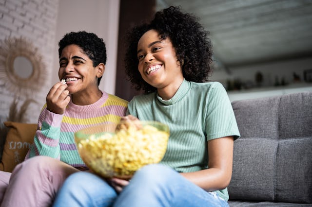 A mother and daughter watch a movie at home.