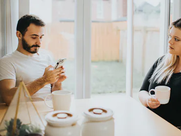 A couple looks tense at the breakfast table.