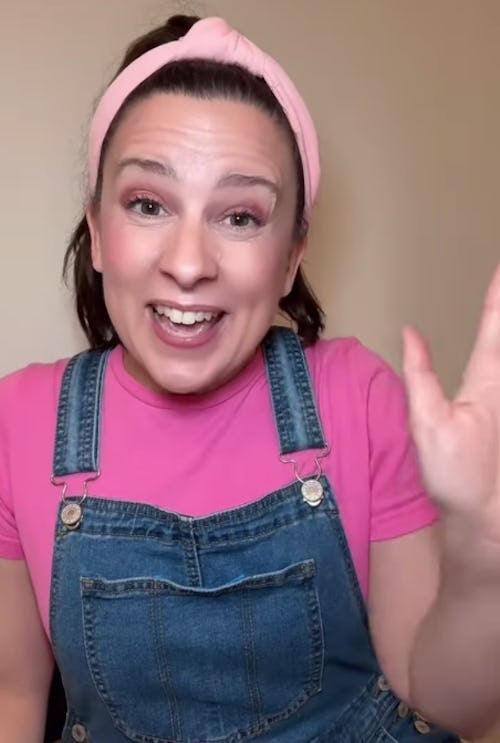 Miss Rachel waves, smiling, in her trademark overalls and pink t-shirt.