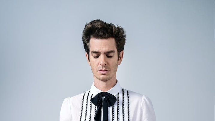 Young man with a contemplative expression, wearing a white shirt with black suspenders and a dark bo...
