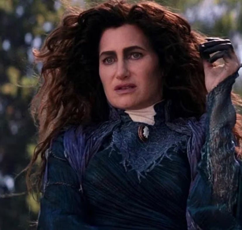 A woman with curly hair, dressed in a medieval blue-green outfit, looking distressed in a snowy fore...