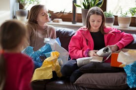 A group of teens open birthday presents on the couch.