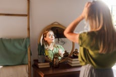 A woman looks at herself in the mirror.