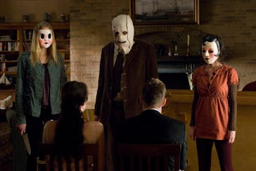Three masked killers stand in front of an innocent couple in 'The Strangers'