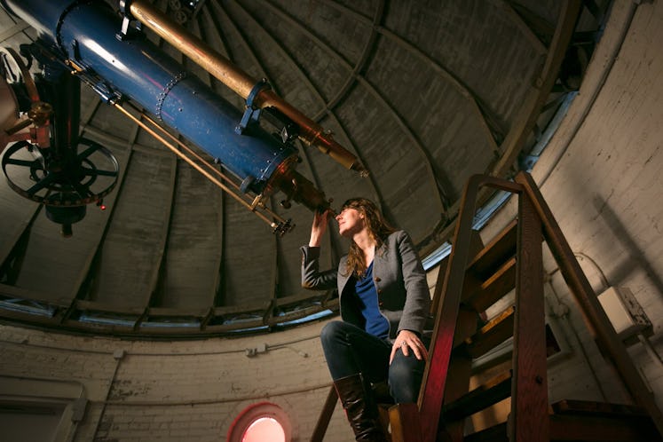 photo of a woman looking through a telescope