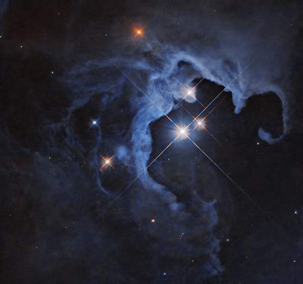 Three bright stars with diffraction spikes shine near the center-right of the image, illuminating ne...