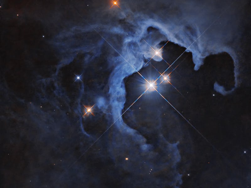 Three bright stars with diffraction spikes shine near the center-right of the image, illuminating ne...