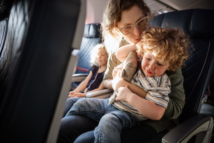 A mother comforts her child on an airplane.