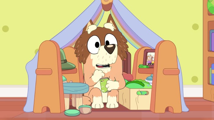 Mort sits in a child's blanket fort, smiling.