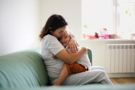 A woman hugs her child in her home.