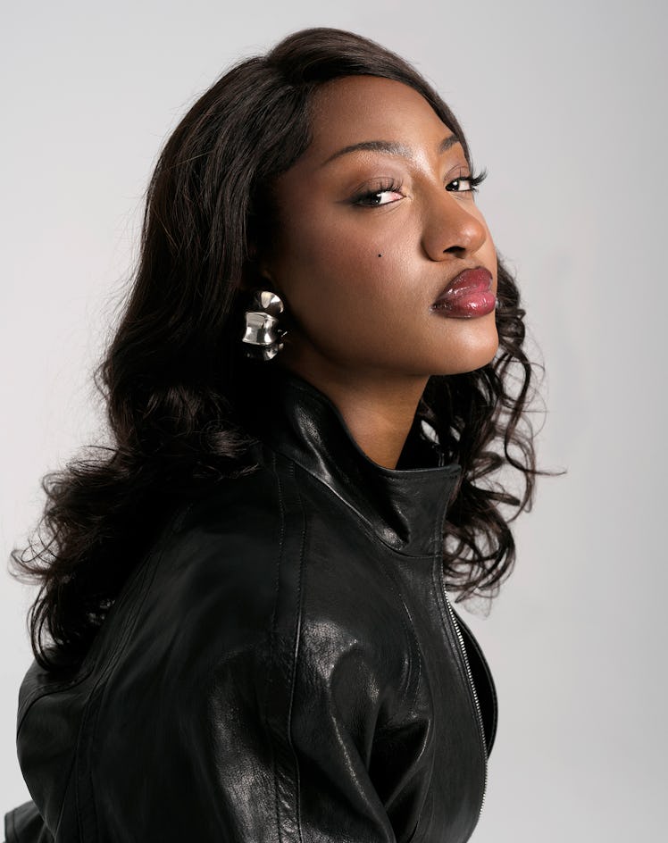 Singer Tems wears a black leather jacket and earrings.