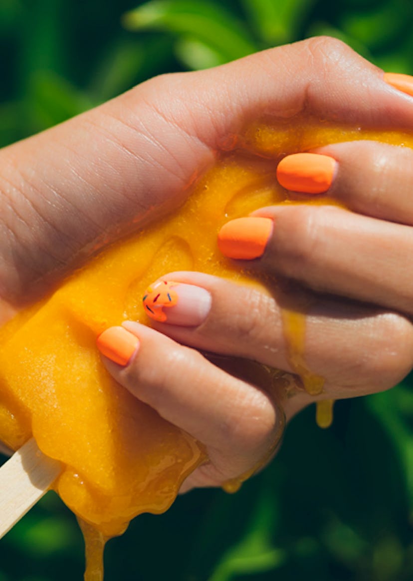 Summer nail trends include neon polish colors, as seen in this bright orange popsicle themed manicur...