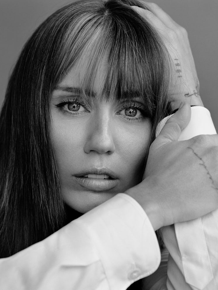 Miley Cyrus wears a white button down shirt.