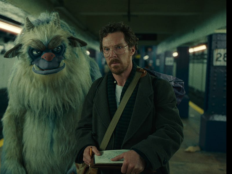 A man in a coat stands in a subway station beside a large, blue-faced creature resembling a yeti. Th...