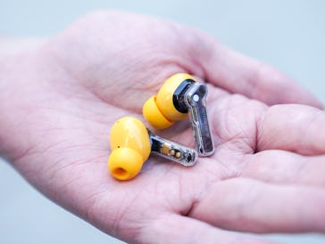 Yellow Nothing Ear A wireless earbud in a hand.