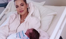Khloe Kardashian holding her newborn son Tatum. 