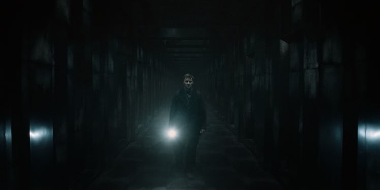 a man holding a lantern walks through a dark corridor lined with doors