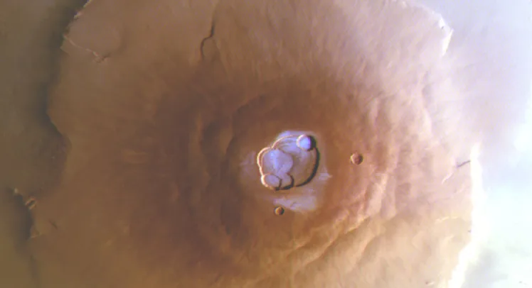 view of a volcano from above, with blue frost in the caldera at the top