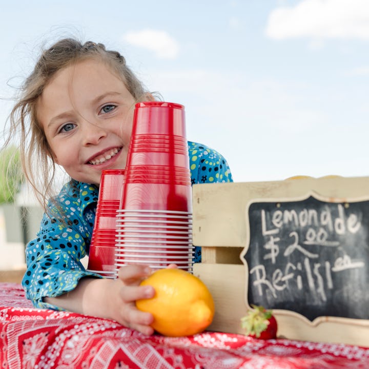 A young girl sells lemonade at her lemonade stand.