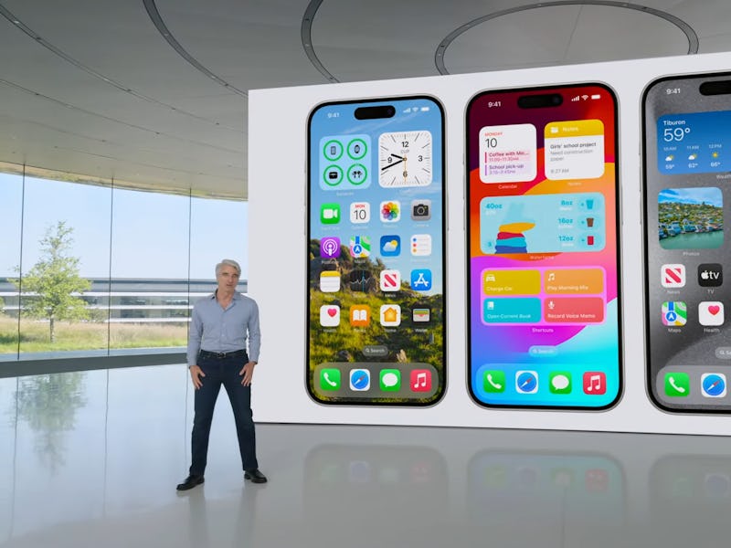 A man stands beside three oversized smartphone models showcasing colorful screen interfaces inside a...