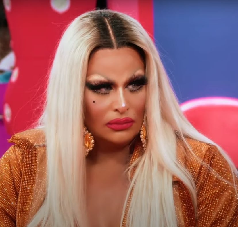 Drag queen with blonde hair and meticulous makeup wears a shimmering golden outfit, looking pensive ...