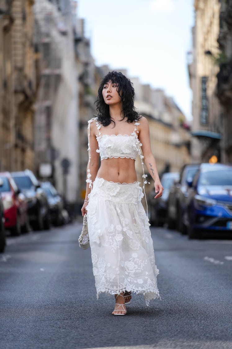 Xiayan Guo wears a full Zimmermann white look with floral details and embroidery, a crop top / tank ...