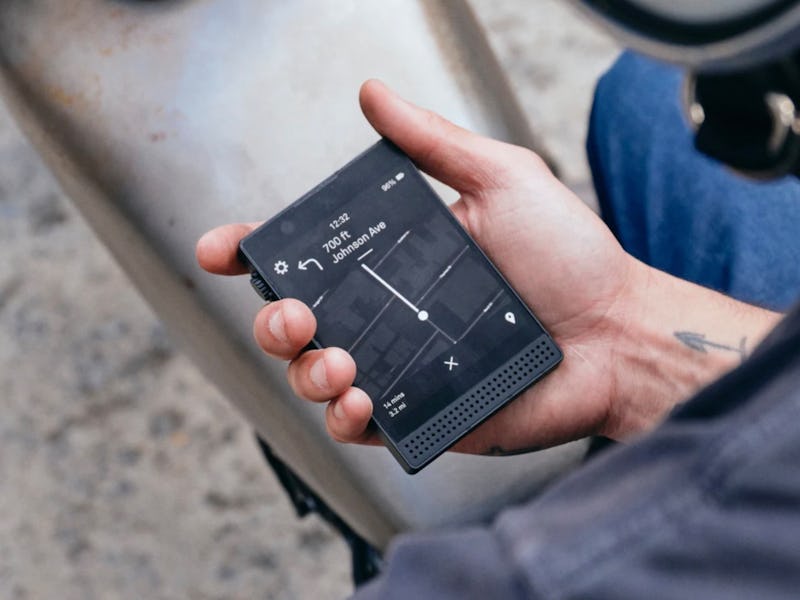 Person holding a modern, portable audio recording device with a digital display, controls visible, i...