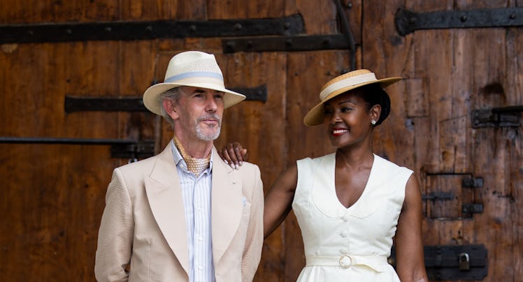 Guillaume Bo wears hat, brown suit & Angelique Noire wears straw hat, vest, skirt, bag during Pitti ...