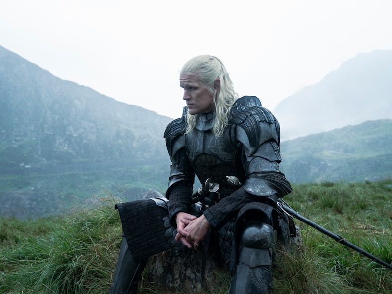 A person in medieval armor and long white hair kneels in a misty, mountainous landscape, holding a s...