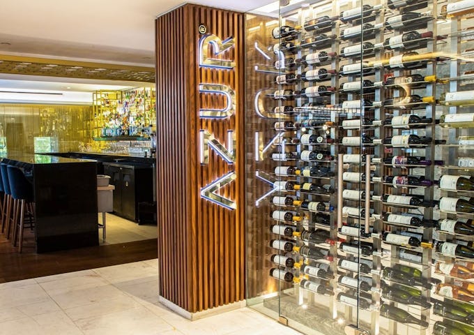Modern restaurant wine cellar with lit-up 'AZUR' sign and glass walls displaying an extensive wine collection.