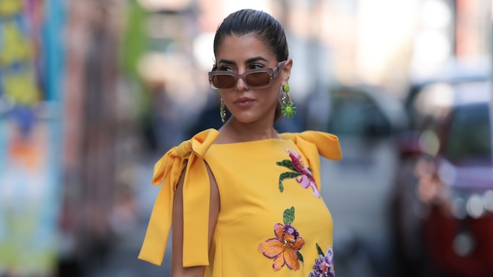NEW YORK, NEW YORK - SEPTEMBER 12: A Fashion Week guest is seen wearing beige sunglasses from Carolina Herrera, green flower earrings, a sleeveless yellow mini dress with floral embroideries, an orange leather bag from Carolina Herrera before the Carolina Herrera Spring Summer 2024 Runway Show on September 12, 2023 in New York City. (Photo by Jeremy Moeller/Getty Images)
