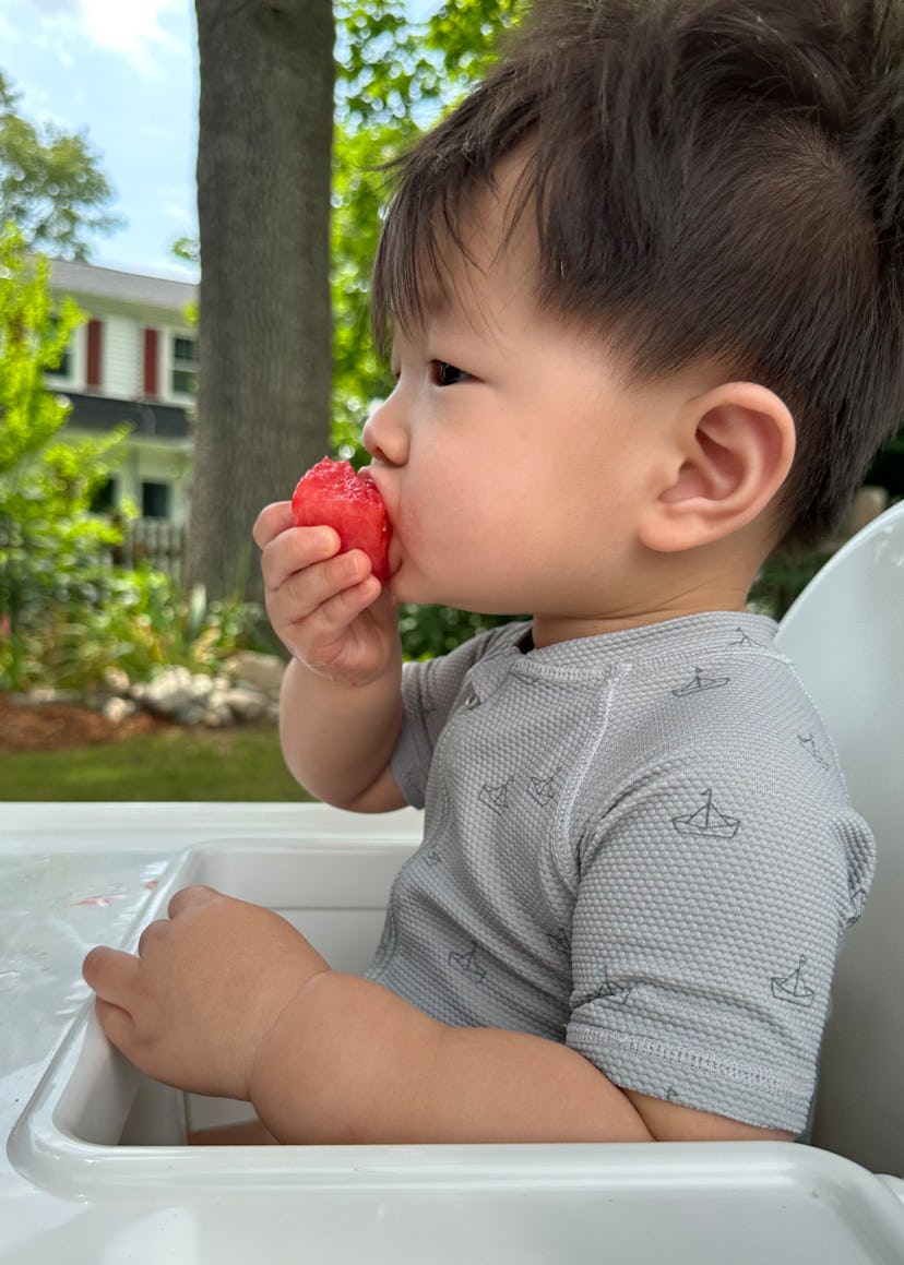 A photograph of a toddler eating a strawberry.