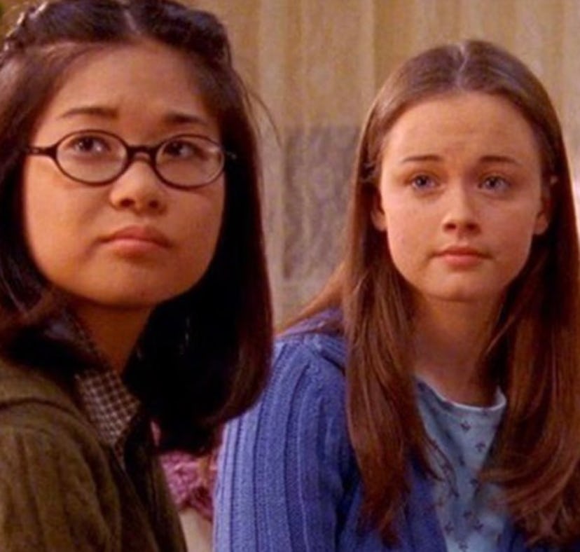 Two young girls, one with glasses and a green jacket, the other in a blue sweater, looking slightly ...