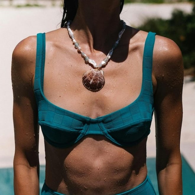 model wears jennifer behr pearl & seashell necklace and teal bikini