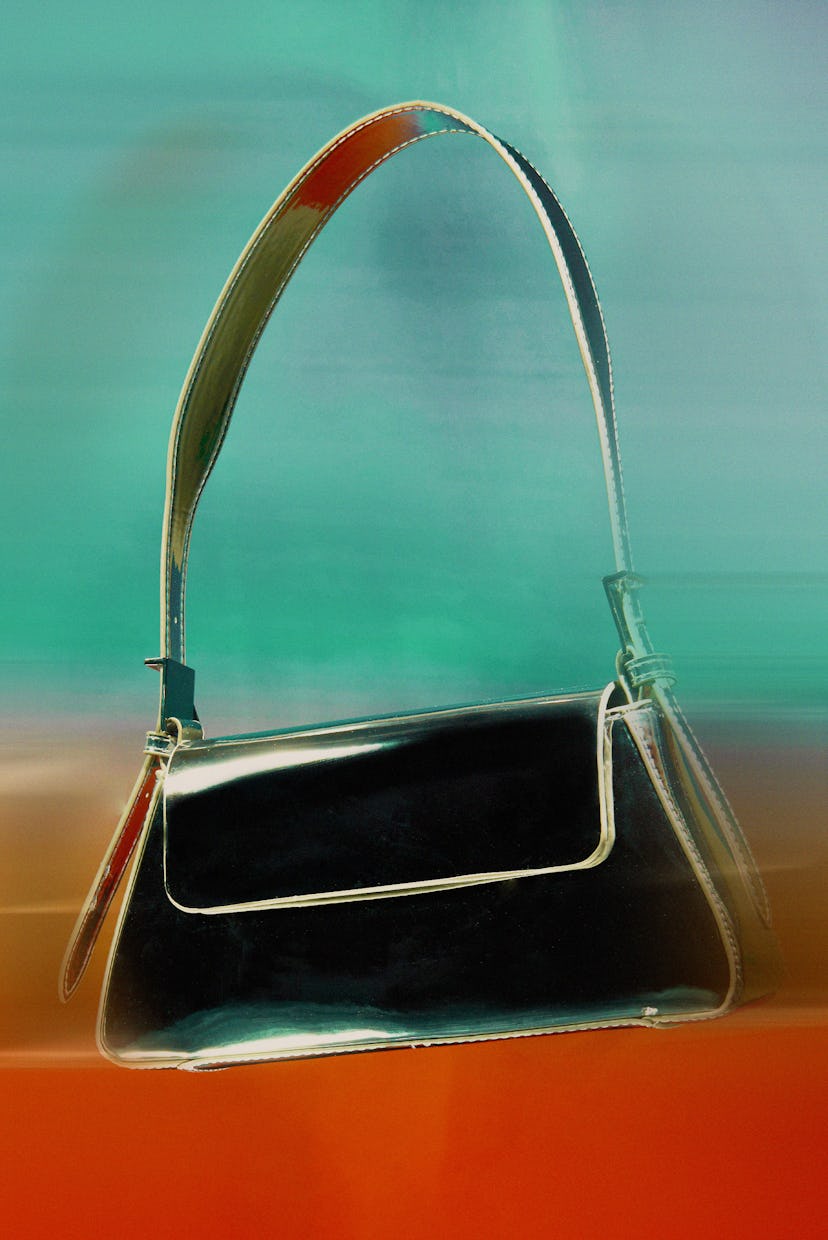 Vintage black handbag with a metal frame and a slender strap, displayed against a softly blurred mul...