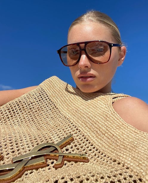 Elsa Hosk carries a raffia Saint Laurent tote to the beach.