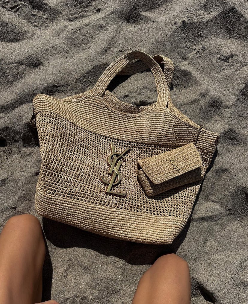 Elsa Hosk carries a raffia Saint Laurent tote to the beach.
