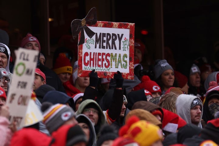 Crowd of Kansas City Chiefs fans with a sign reading "Merry Chiefsmas" at a football game.
