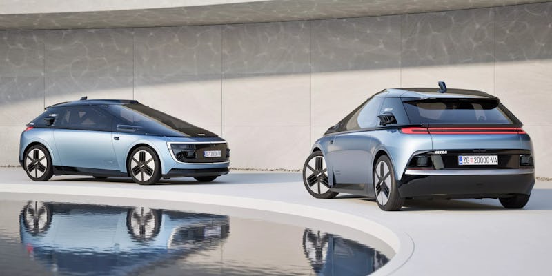 Two modern electric cars displayed side by side, one blue and one gray, with sleek designs reflected...