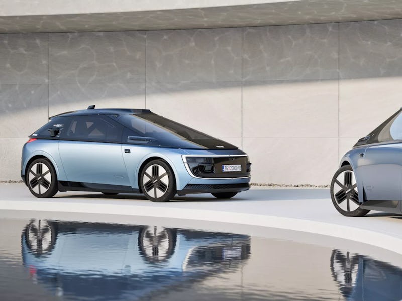 Two modern electric cars displayed side by side, one blue and one gray, with sleek designs reflected...