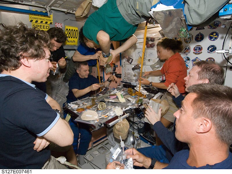 Eight of a total group of 13 astronauts and cosmonauts are pictured at meal time aboard the Interna...