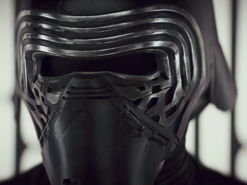 Close-up of a person wearing a dark, futuristic helmet with vertical, ribbed details, behind blurred...