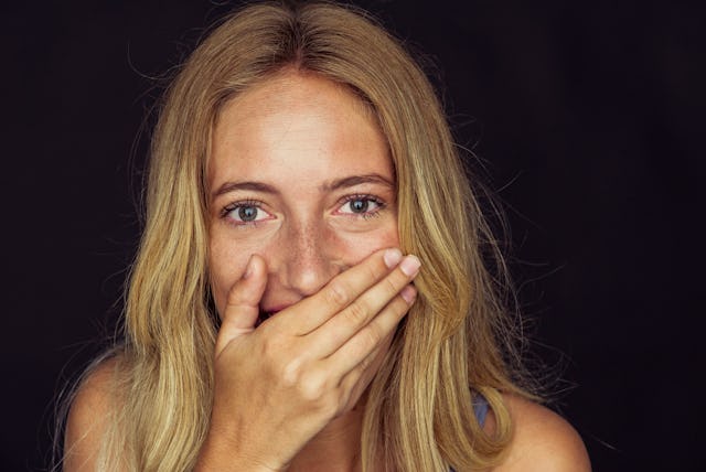 A woman reacts to something with shock laughter.