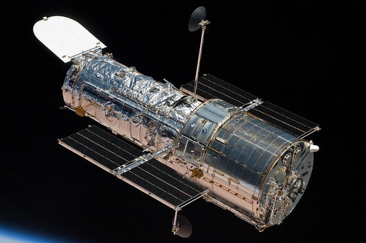 The Hubble Space Telescope shines like a cylindrical figurine of sterling silver against the dark ba...